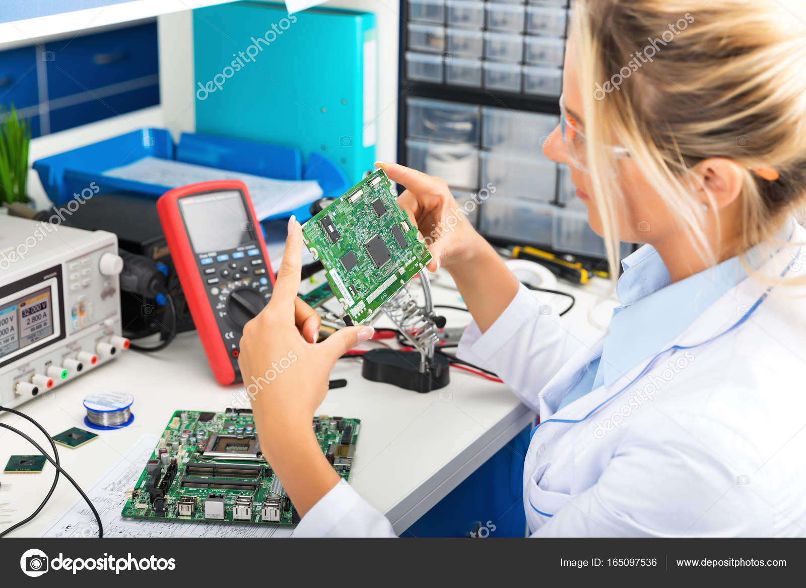 Female electronic engineer checking circuit board in laboratory Stock