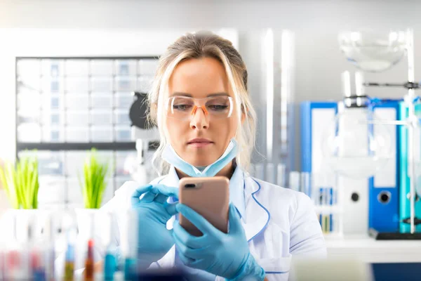 Молодая привлекательная женщина-ученый использует смартфон в лаборатории — стоковое фото