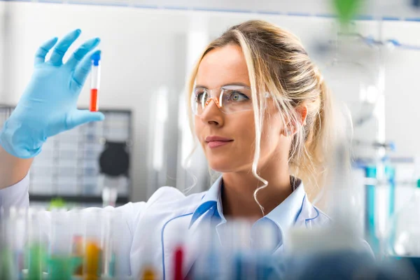 Jonge aantrekkelijke vrouwelijke wetenschapper examiming reageerbuis met subst — Stockfoto