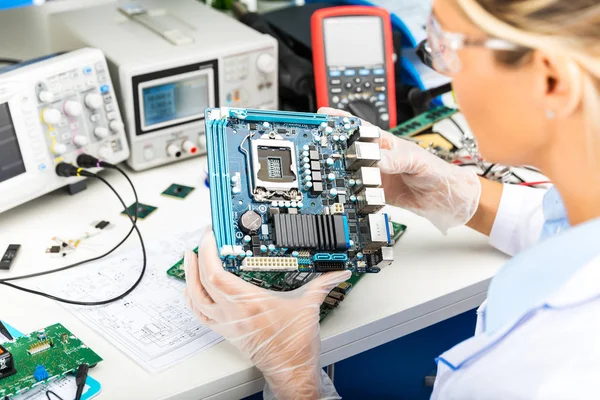 Vrouwelijke elektronische ingenieur de systeemkaart van de computer in het lab onderzoeken — Stockfoto