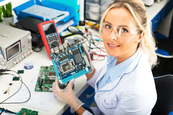 Kvinnliga elektroniska ingenjör håller datormoderkort i händer — Stockfoto