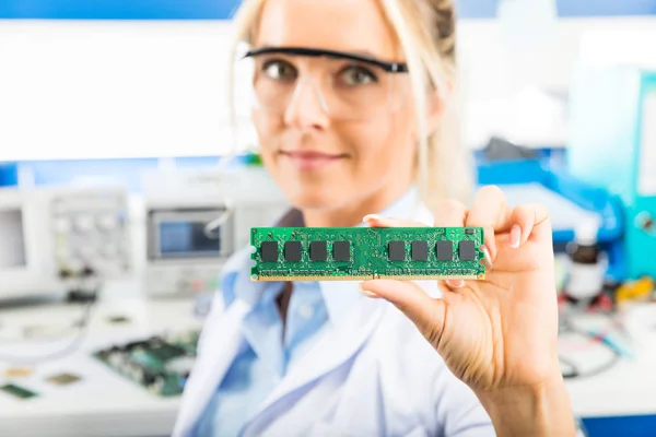 Young female electronic engineer holding memory module in hand — Stock Photo, Image