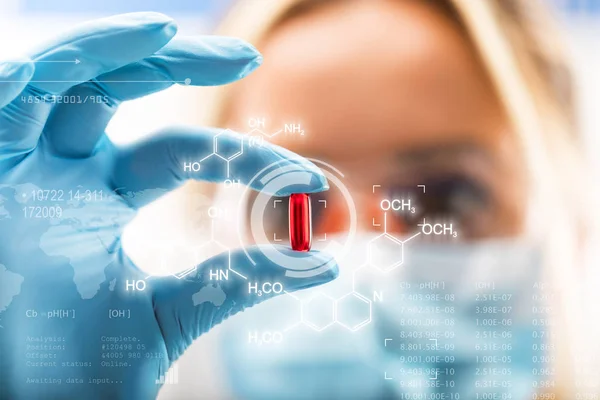 Νέοι ελκυστική γυναίκα επιστήμονας κρατώντας ένα κόκκινο διαφανές χάπι — Φωτογραφία Αρχείου