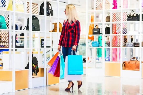 Ung kvinna med shoppingkassar i fashion store — Stockfoto