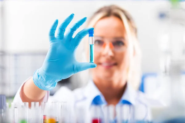 Jovem cientista atraente examinando tubo de ensaio com subst — Fotografia de Stock