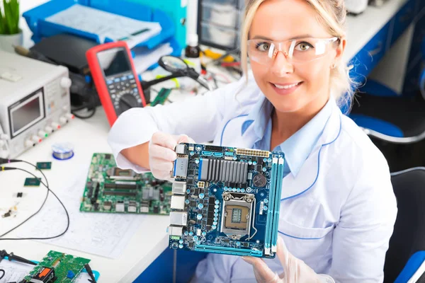 Kvinnliga elektroniska ingenjör håller datormoderkort i händer — Stockfoto