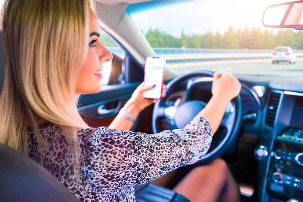 Mladá žena pomocí chytrého telefonu při jízdě autem — Stock fotografie