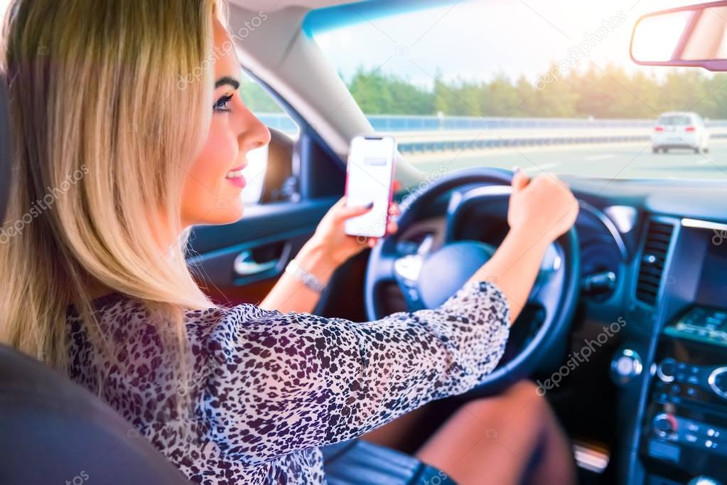 Young woman using a smartphone while driving a car