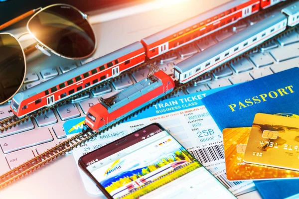 Trem de brinquedo, bilhetes, passaporte e cartão bancário no laptop ou notebook — Fotografia de Stock