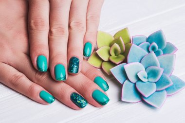 Turkuaz tırnak sanat ile tinsels Beyaz ahşap zemin üzerinde