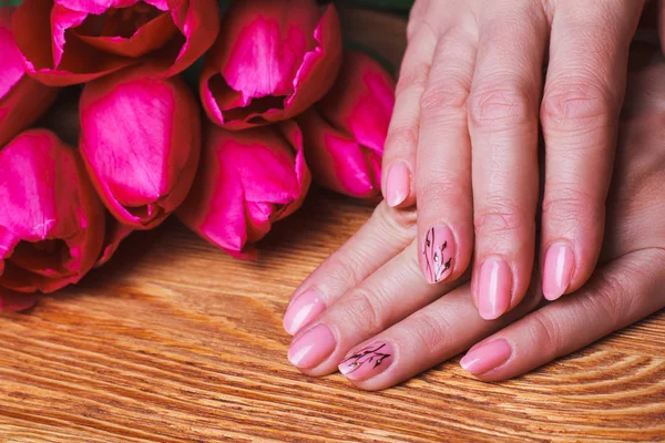 Pink nail art with flowers on wood background