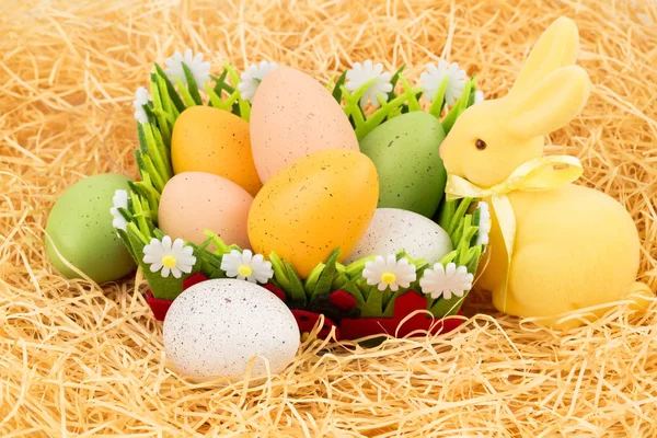 复活节彩蛋在篮子里 黄色兔子在稻草背景上 — 图库照片