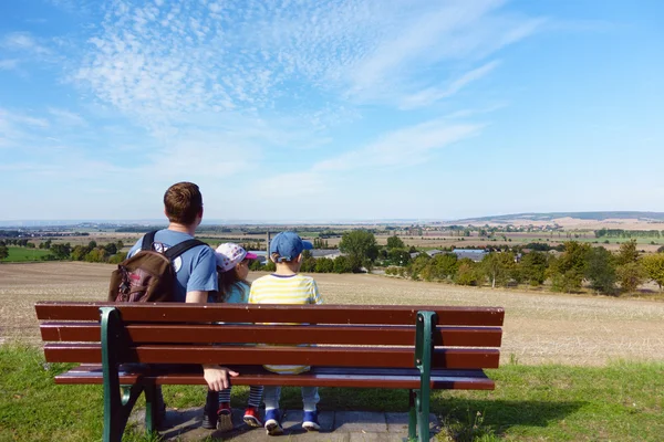 Glückliche Familie sitzt an Sommertagen auf Bank auf der Wiese — Stockfoto