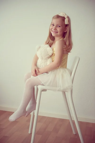 Pretty smiling ballet girl in white-yellow tutu sitting on chair — Stock Photo, Image