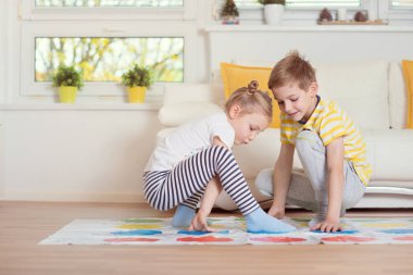 Two happy children playing exciting game at home clipart