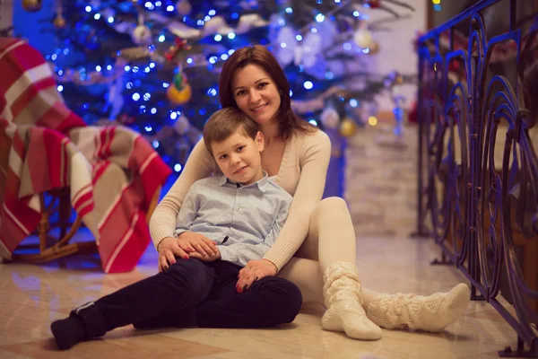 Dość młoda matka siedzi z synem szczęśliwy w santa hat — Zdjęcie stockowe