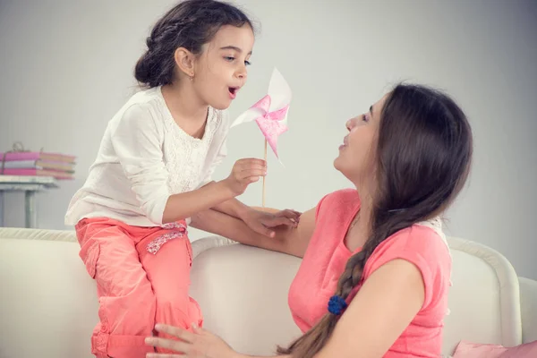 Joven madre y pequeña hija linda jugando con el molinete — Foto de Stock