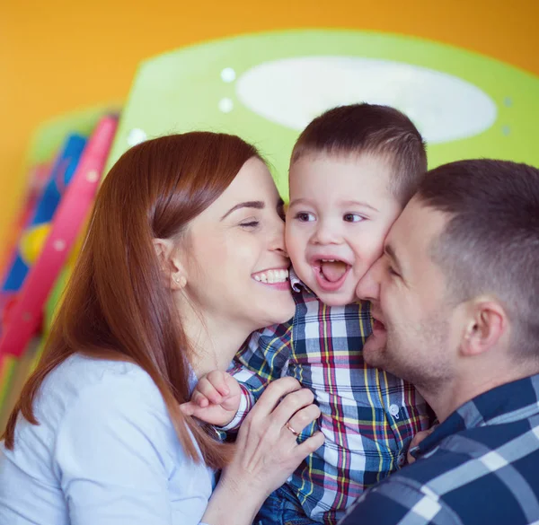 Молодая счастливая семья с маленьким мальчиком, играющим вместе дома — стоковое фото