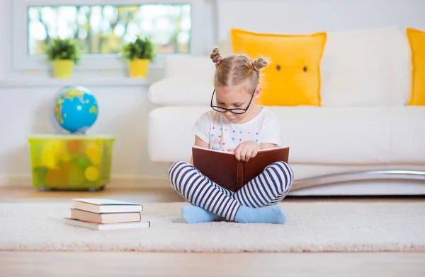 Kitap ile katta oturan zeki küçük kız portresi — Stok fotoğraf