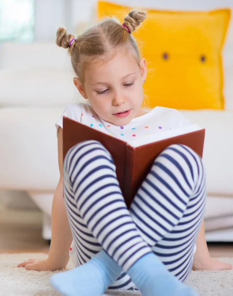 Ritratto di bambina intelligente seduta con libro sul pavimento — Foto Stock