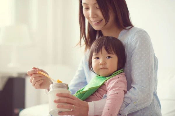 Mutlu Japon anne küçük şirin kızı besleme wih kaşık — Stok fotoğraf