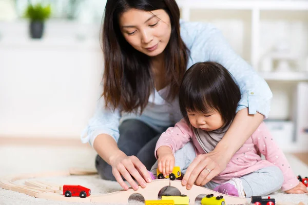 Ganska nöjd japansk mor spela med sitt lilla barn-daught — Stockfoto