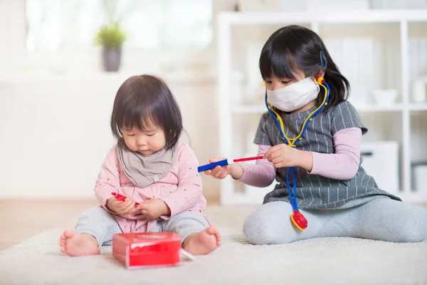 Two happy japanese sisters playing with medical set at home — Stock Photo, Image