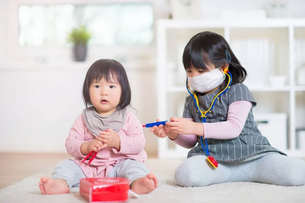 Dos feliz japonés hermanas jugando con médico conjunto en casa — Foto de Stock