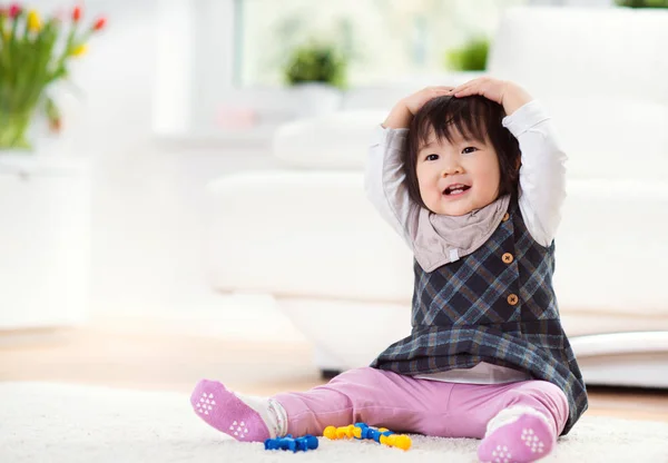 Bastante feliz poco japonés chica jugando en capet en casa —  Fotos de Stock
