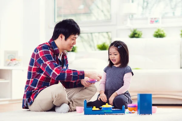 Молодой счастливый отец играет со своей милой маленькой дочкой в доме — стоковое фото