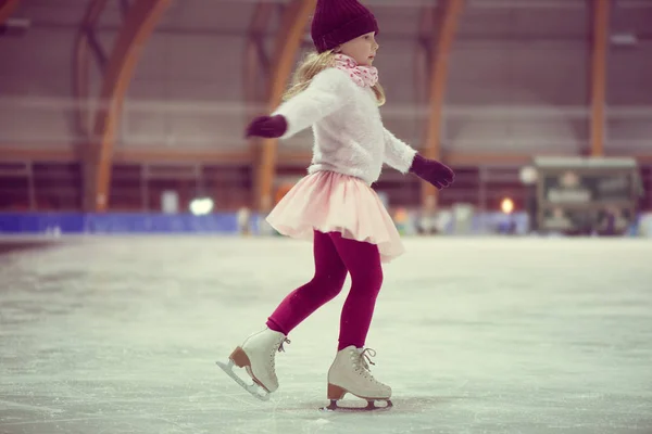 Mooi meisje rolschaatsen in een rode muts, warme handschoenen en trui — Stockfoto