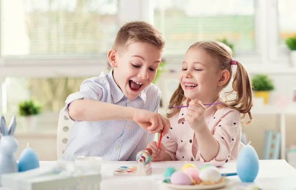 Zwei glückliche Kinder haben Spaß beim Bemalen von Ostereiern in — Stockfoto