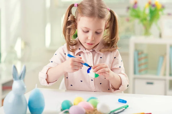 Menina bonita feliz que se diverte durante a pintura de ovos para a Páscoa na primavera — Fotografia de Stock