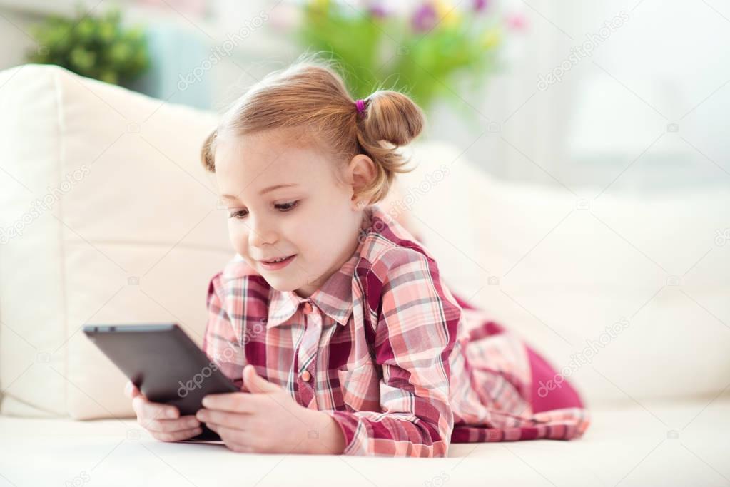 Pretty little child girl  using a digital tablet, looking and sm