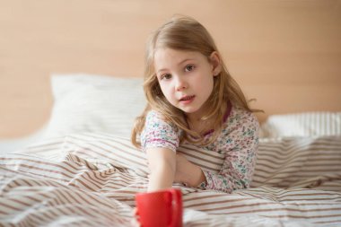 Oldukça küçük çocuk kız yatak içecek çay döşeme hasta