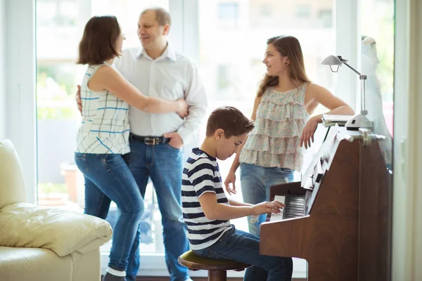 Feliz familia joven escuchando como niños tocan música de piano —  Fotos de Stock