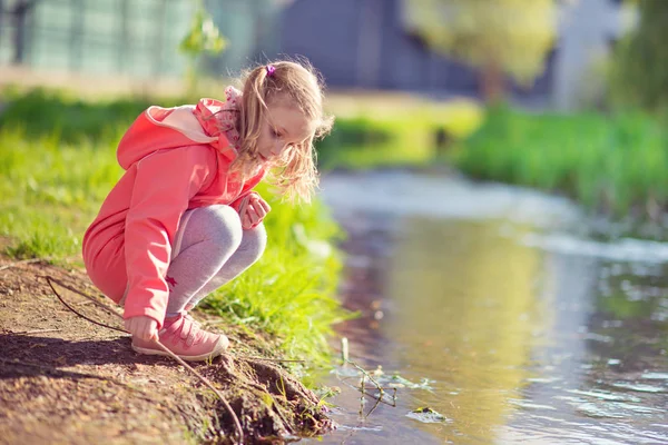Feliz adorable niña jugando cerca del estanque en un día soleado —  Fotos de Stock