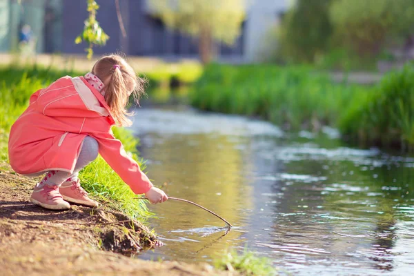 Feliz adorable niña jugando cerca del estanque en un día soleado — Foto de Stock