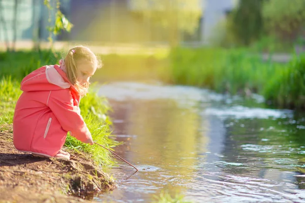 Gelukkig schattig meisje speelt in de buurt van de vijver in zonnige dag — Stockfoto