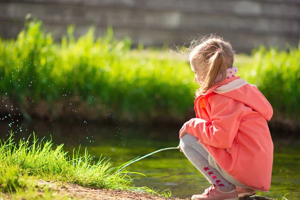 Glücklich liebenswert kleines Mädchen spielt in der Nähe Teich in sonnigem Tag — Stockfoto