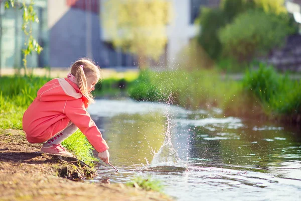 在阳光灿烂的日子在池塘边玩耍的快乐可爱的小女孩 — 图库照片