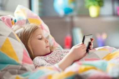 Küçük kız yatakta tablet ile oynamak