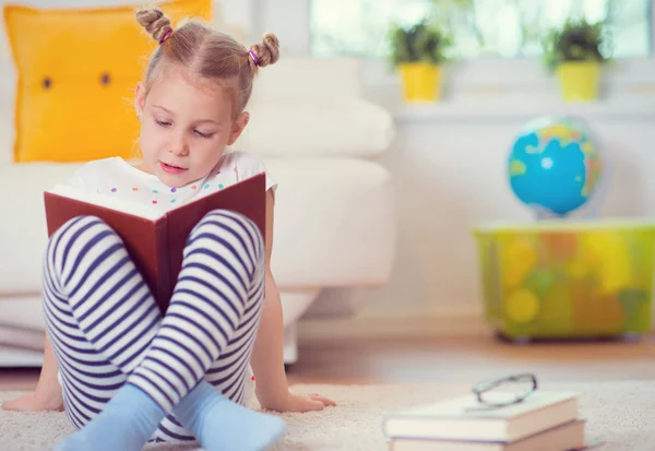 Портрет умной маленькой девочки, сидящей с книгой на полу — стоковое фото
