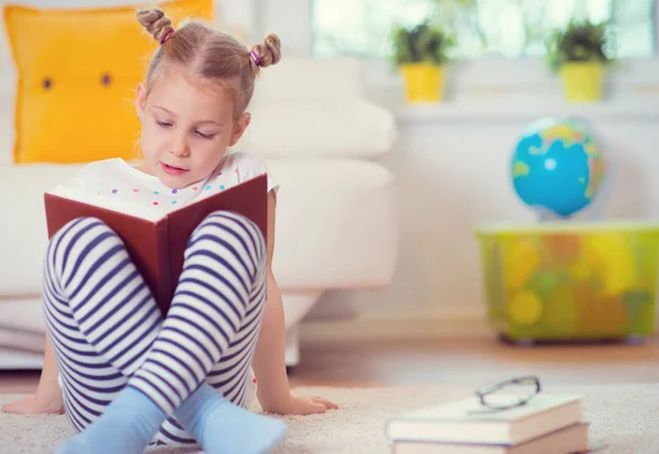 Ritratto di bambina intelligente seduta con libro sul pavimento — Foto Stock