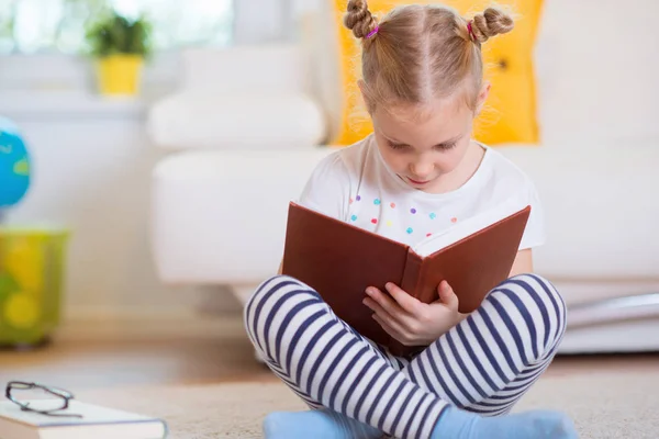 Portrait de petite fille intelligente assise avec un livre sur le sol — Photo