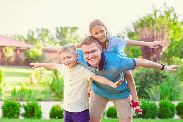 Портрет счастливого отца и двух милых детей, играющих во дворе — стоковое фото