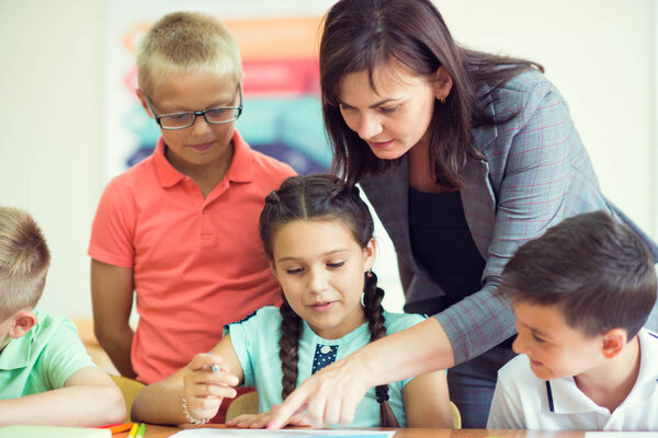 Yong beautiful teacher with group of clewer children in school 