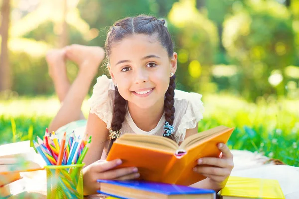 Porträt eines hübschen jungen Mädchens beim Lesen von Buch im Park — Stockfoto