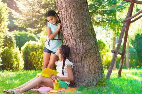 Dwie całkiem małe dziewczynki, czytanie w parku — Zdjęcie stockowe