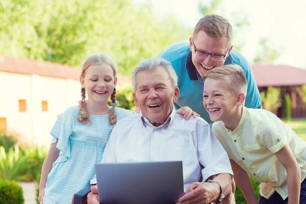Šťastná rodina s dědečkem během Internetu mluví na laptop — Stock fotografie